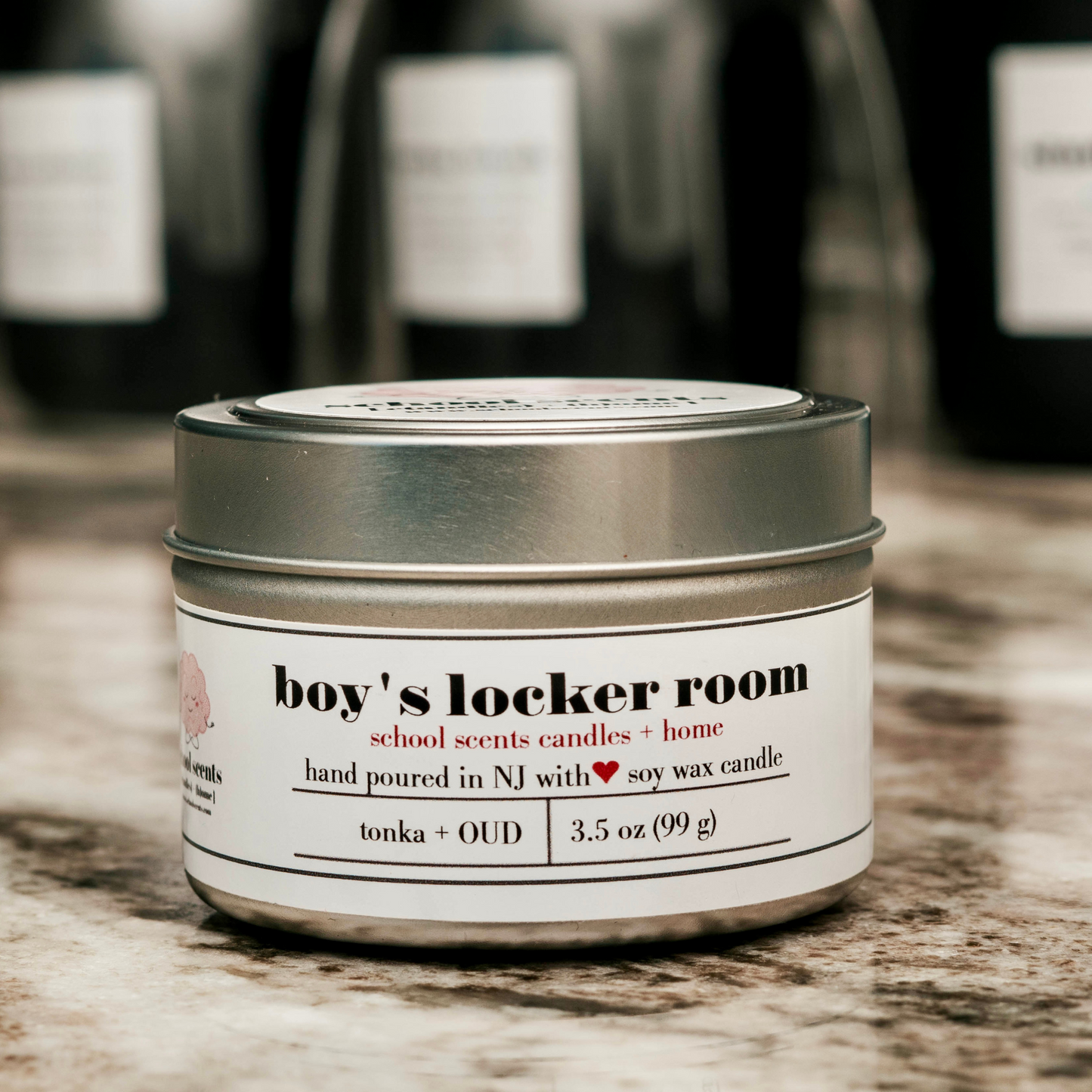 Close up of silver travel tin candle labeled “Boy's Locker Room” on a marble surface