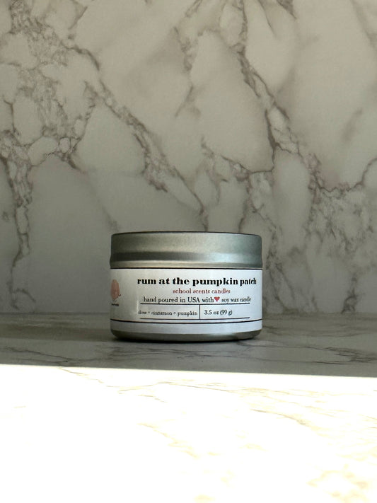Silver travel tin candle labeled “Run at the Pumpkin Patch” on a marble surface