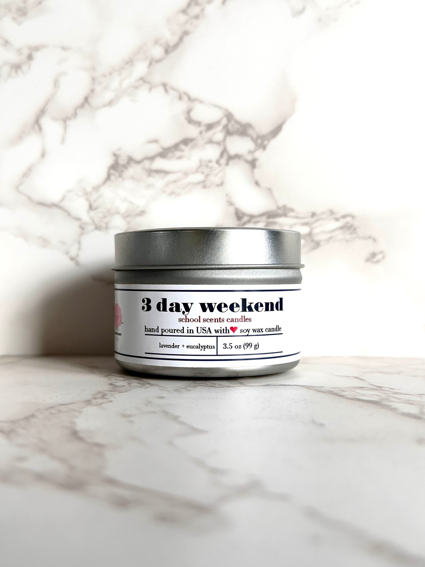 Silver travel tin candle labeled “3 day weekend' on a marble surface