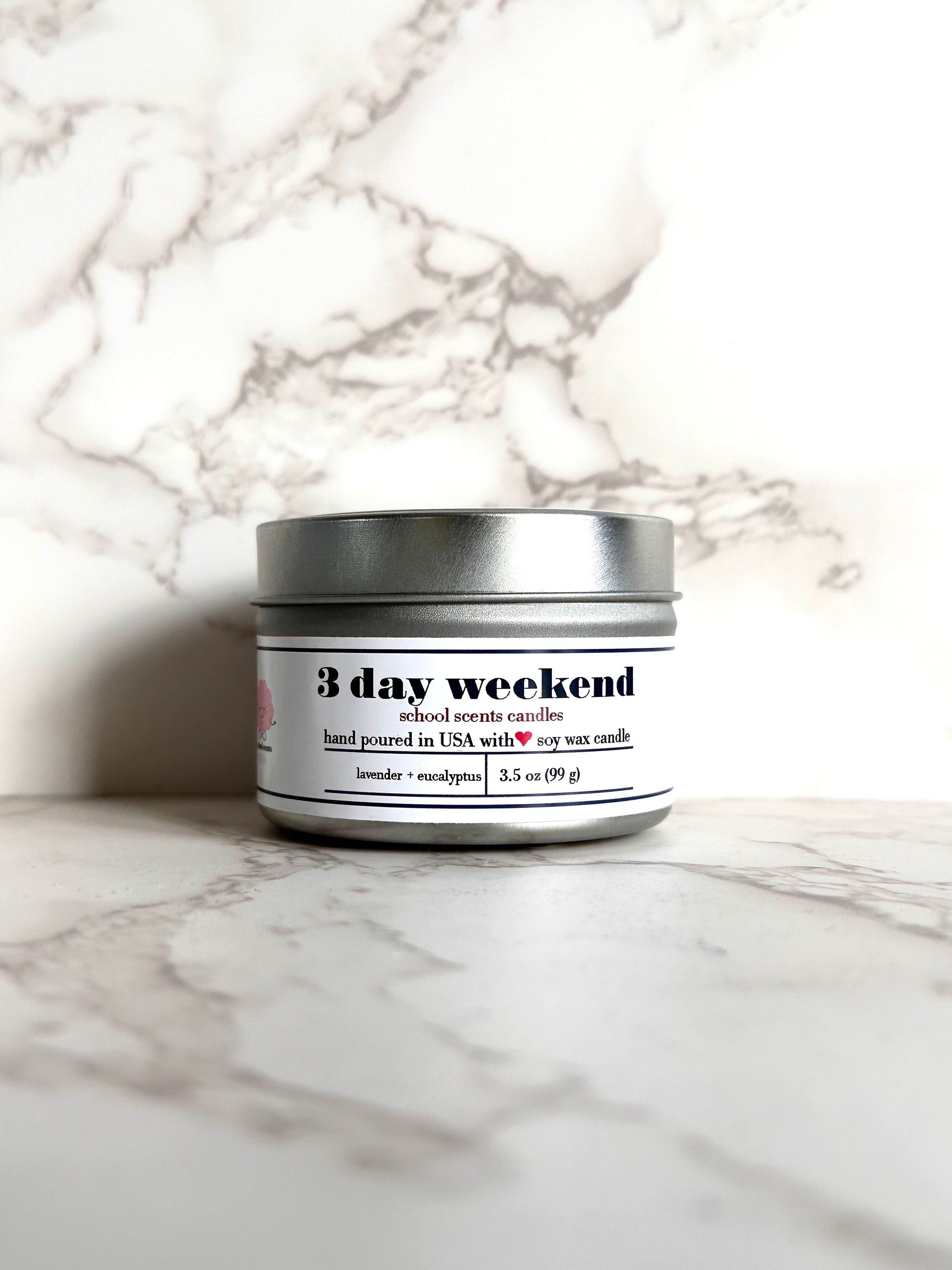 Silver travel tin candle labeled “3 day weekend' on a marble surface