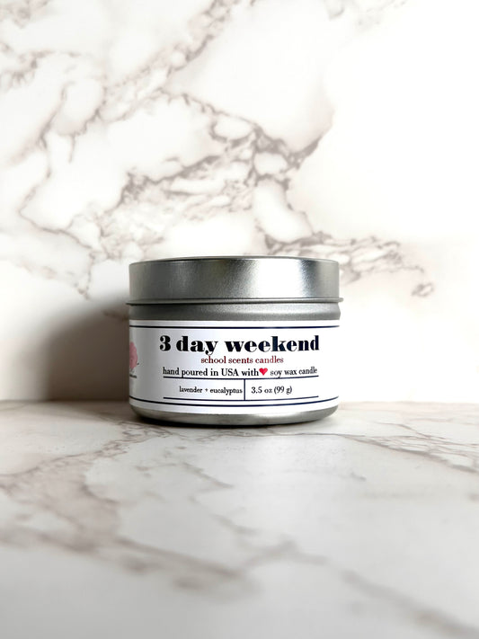 Silver travel tin candle labeled “3 day weekend' on a marble surface